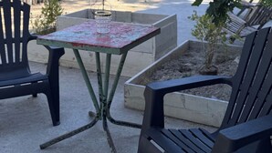 A patio with two black chairs, a small table with a glass, and a wooden fence. - Motel - Usine à Gaz (Bourgueil)