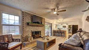 A living room with a brick fireplace, a ceiling fan, and a leather sofa. - Luxury 3BR Getaway 2 Master Suites Pool & More, Great Location (Stone Mountain)