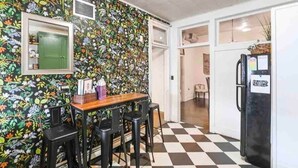 A kitchen with a checkered floor, a wooden table with chairs, a refrigerator, and a wall with a floral pattern. - The Honesdale Loft - downtown historic Main St (Honesdale)