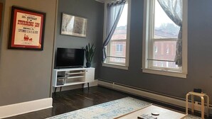 A living room with a flat-screen TV, a plant, and a framed picture on the wall. - The Honesdale Loft - downtown historic Main St (Honesdale)