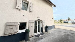 Un bâtiment à la façade beige, doté d’une porte d’entrée en verre et de deux fenêtres avec volets.