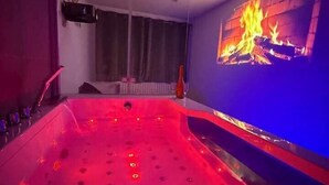 Une pièce dotée d’un grand plancher chauffant, d’une cheminée fixée au mur et d’une fenêtre avec des rideaux.