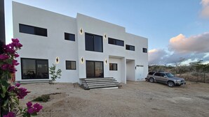 Un bâtiment moderne à deux étages, avec une allée en gravier et un VUS garé devant.