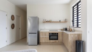 Eine moderne Küche mit einem Edelstahl-Kühlschrank, Holzschränken, einem eingebauten Backofen und einer schwarzen Mülltonne.