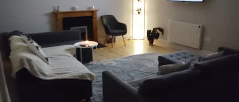 Una sala de estar con chimenea, televisor y un área de estar confortable.