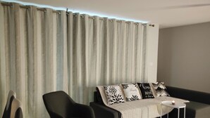 Una sala moderna con un sofá gris, un sillón negro y una pequeña mesa blanca con una vela.