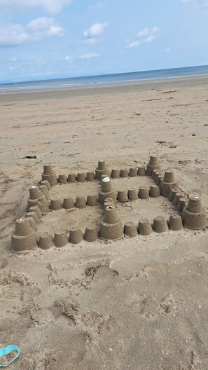 A sandy beach with a large sand sculpture of a face. - 2 Bedroom Apartment 4-6 People-coastal Comfort (Balbriggan)