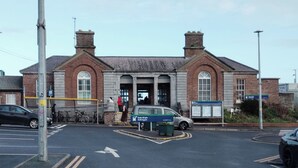 A building with a traditional brick facade, a central entrance with a large door, and a sign indicating it is a public facility. - 2 Bedroom Apartment 4-6 People-coastal Comfort (Balbriggan)