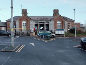 A building with a traditional brick facade, a central entrance with a large door, and a sign indicating it is a public facility. - 2 Bedroom Apartment 4-6 People-coastal Comfort (Balbriggan)
