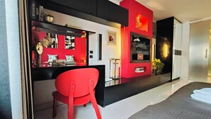 Una sala de estar moderna con una butaca roja, un televisor de pantalla plana y una chimenea.