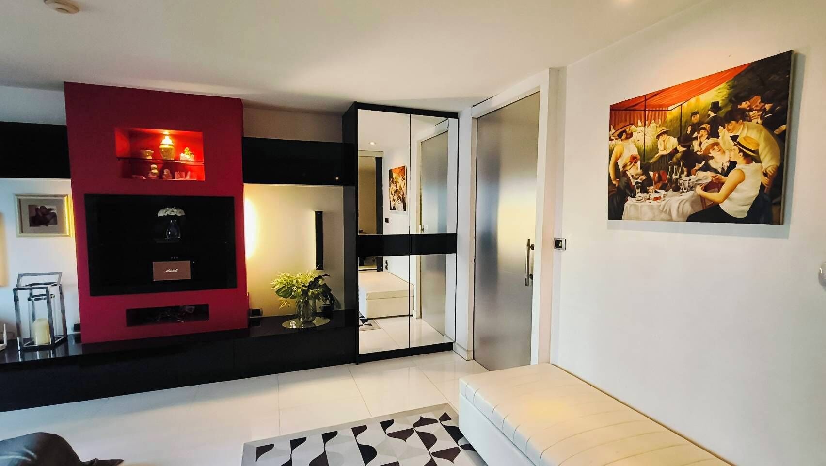 Una sala de estar moderna con una pared de acento roja, una mesa de centro de vidrio y un cuadro en la pared.