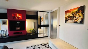 Una sala de estar moderna con una pared de acento roja, una mesa de centro de vidrio y un cuadro en la pared.