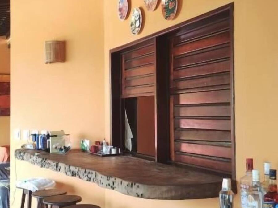 A bar area with stools, a counter, and a wall decorated with plates.