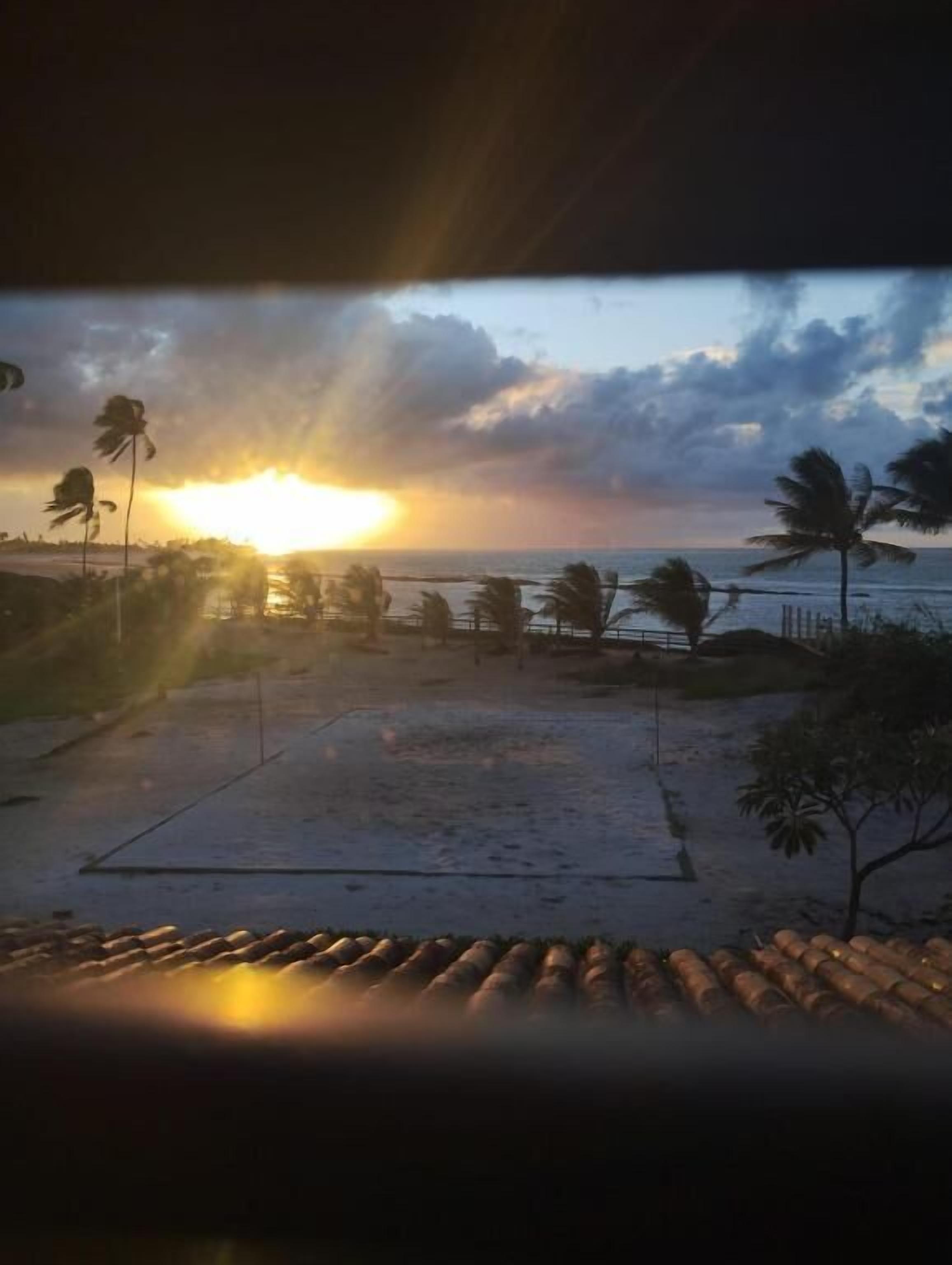 Vista sulla spiaggia con palme e un tramonto.