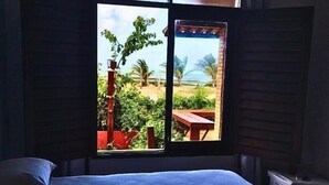 Una cama con vista a un paisaje tropical a través de una ventana.