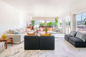 A spacious living area with a large sofa, a coffee table, and a dining area with chairs. - Big apt 4beds with terrace, 15 mins to Lisbon (Almada)