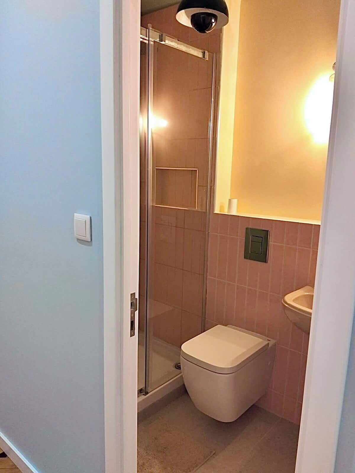 Een badkamer met een douchecabine van glas, een toilet en een wastafel.