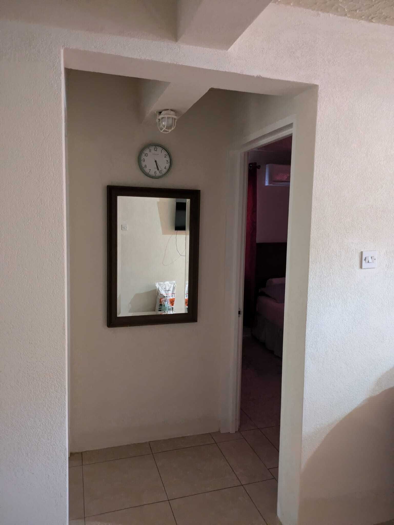 Un pasillo con un reloj y un espejo en la pared.