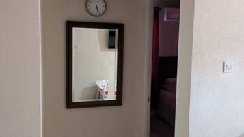 Un pasillo con un reloj y un espejo en la pared.