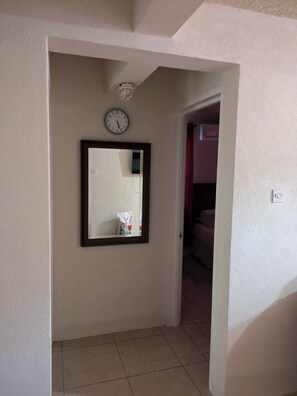 Ein Flur mit einer Uhr und einem Spiegel an der Wand.