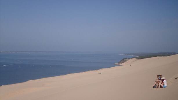 Paisagem desértica com dunas de areia e um céu azul claro.