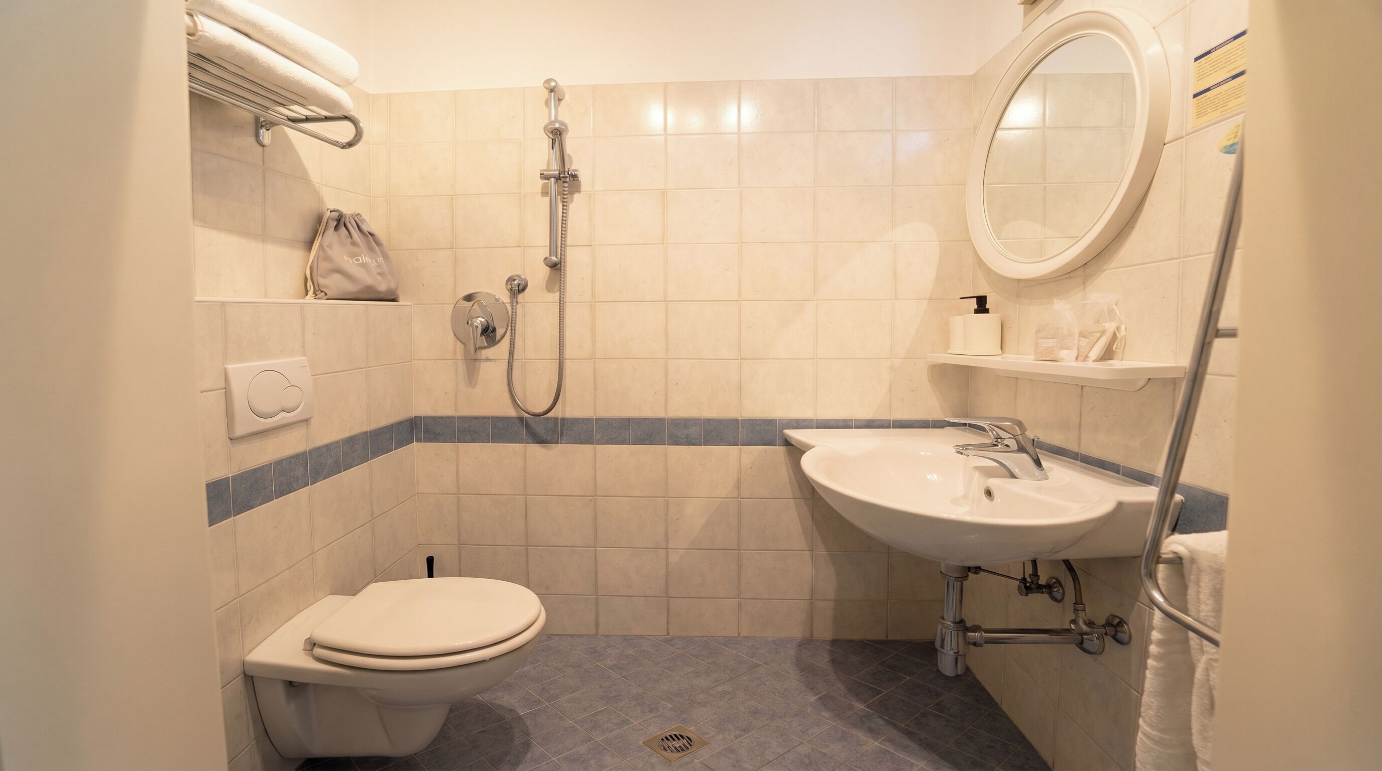 A bathroom with a toilet, sink, shower, and a towel rack.