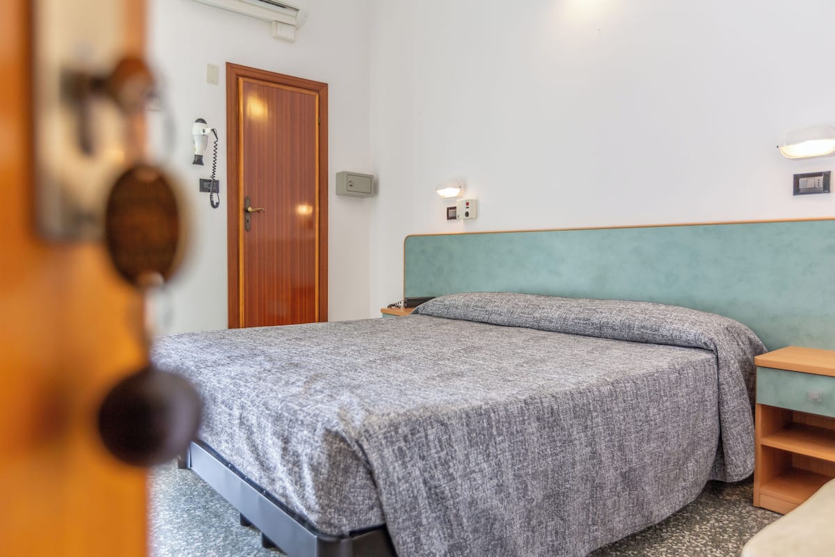A bedroom with a bed, bedside tables, and a wooden door.