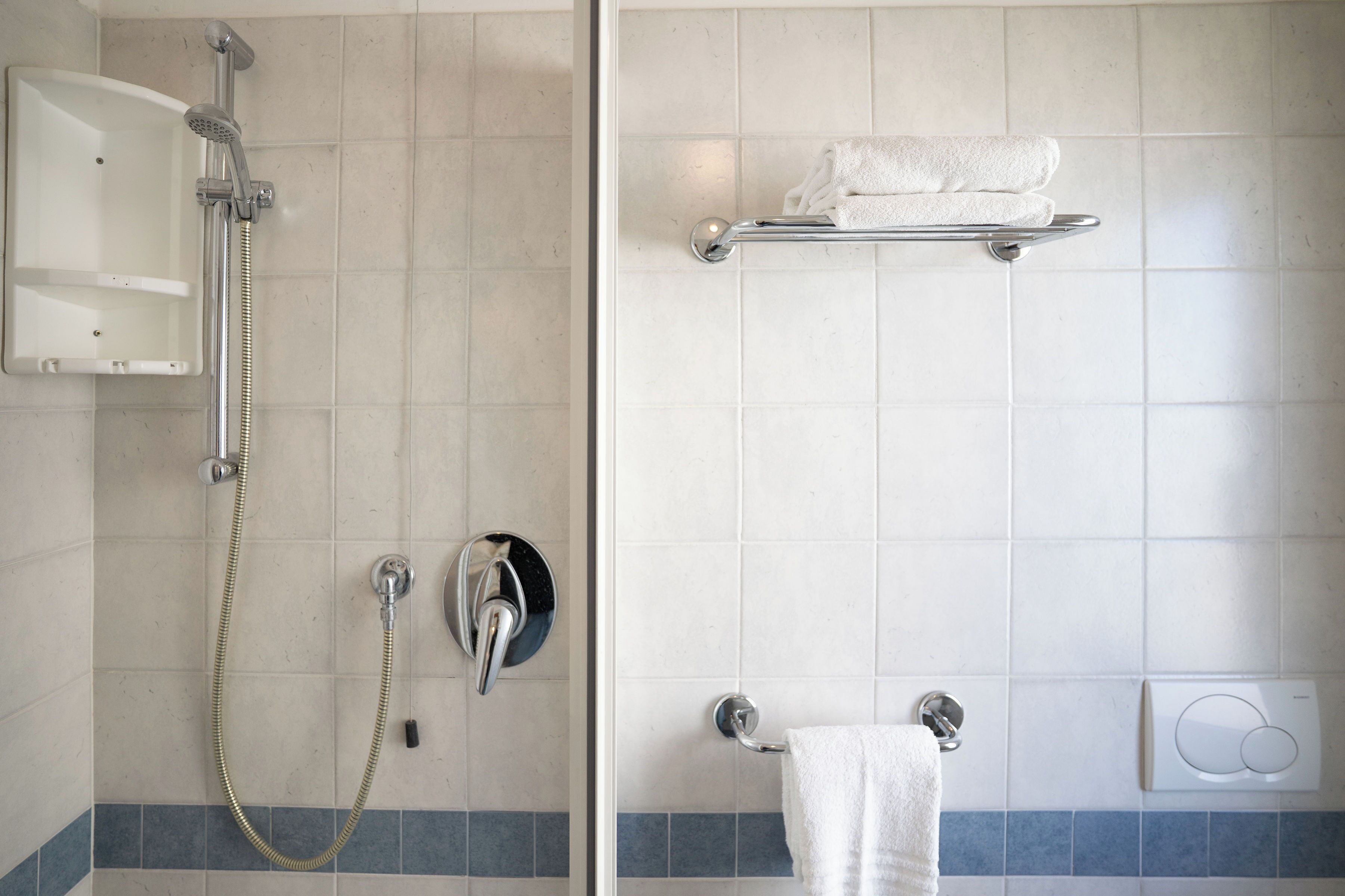 Ein Badezimmer mit Dusche, Handtuchhalter und Handtuchspender.