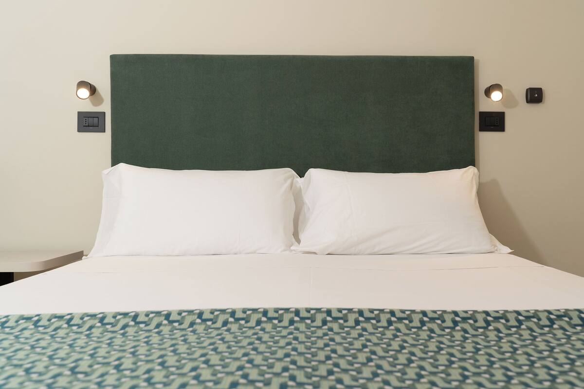 A bed with a green headboard, white pillows, and a patterned bedspread.