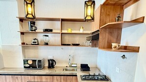Eine moderne Küche mit einer zentralen Kochinsel, zwei Barhocker, Holzböden und Pendelleuchten.