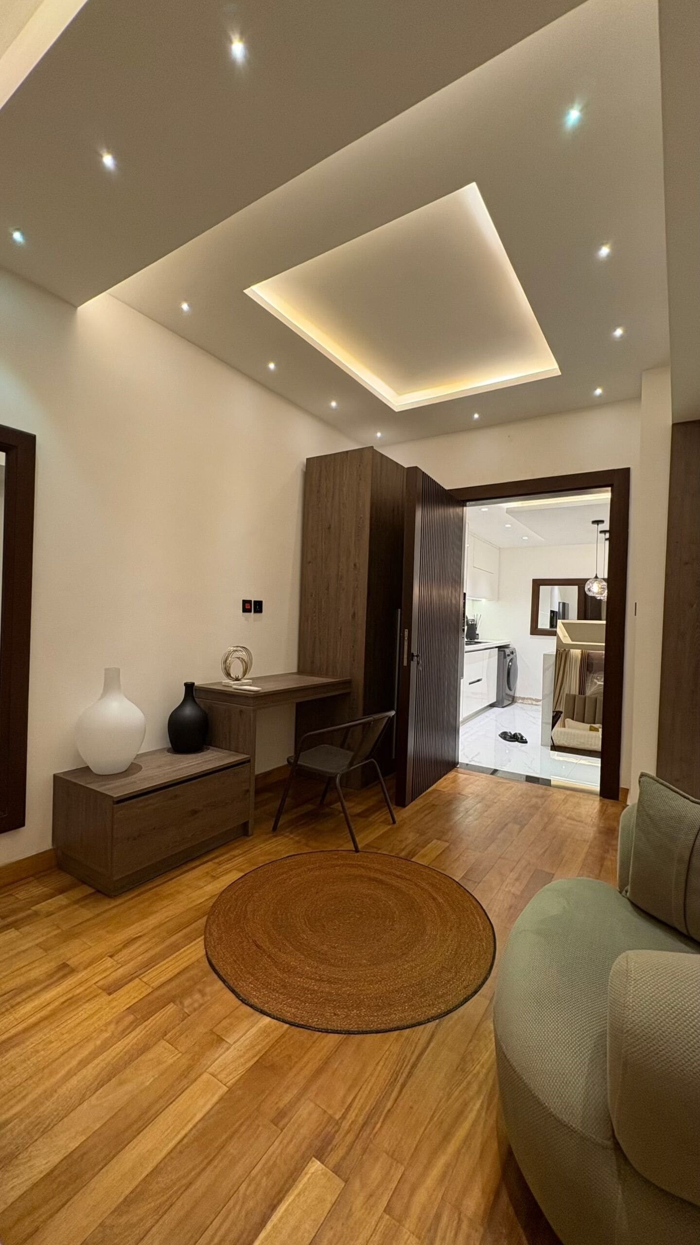 Un salon moderne avec un plancher en bois, un tapis rond, un canapé, un bureau et un meuble.