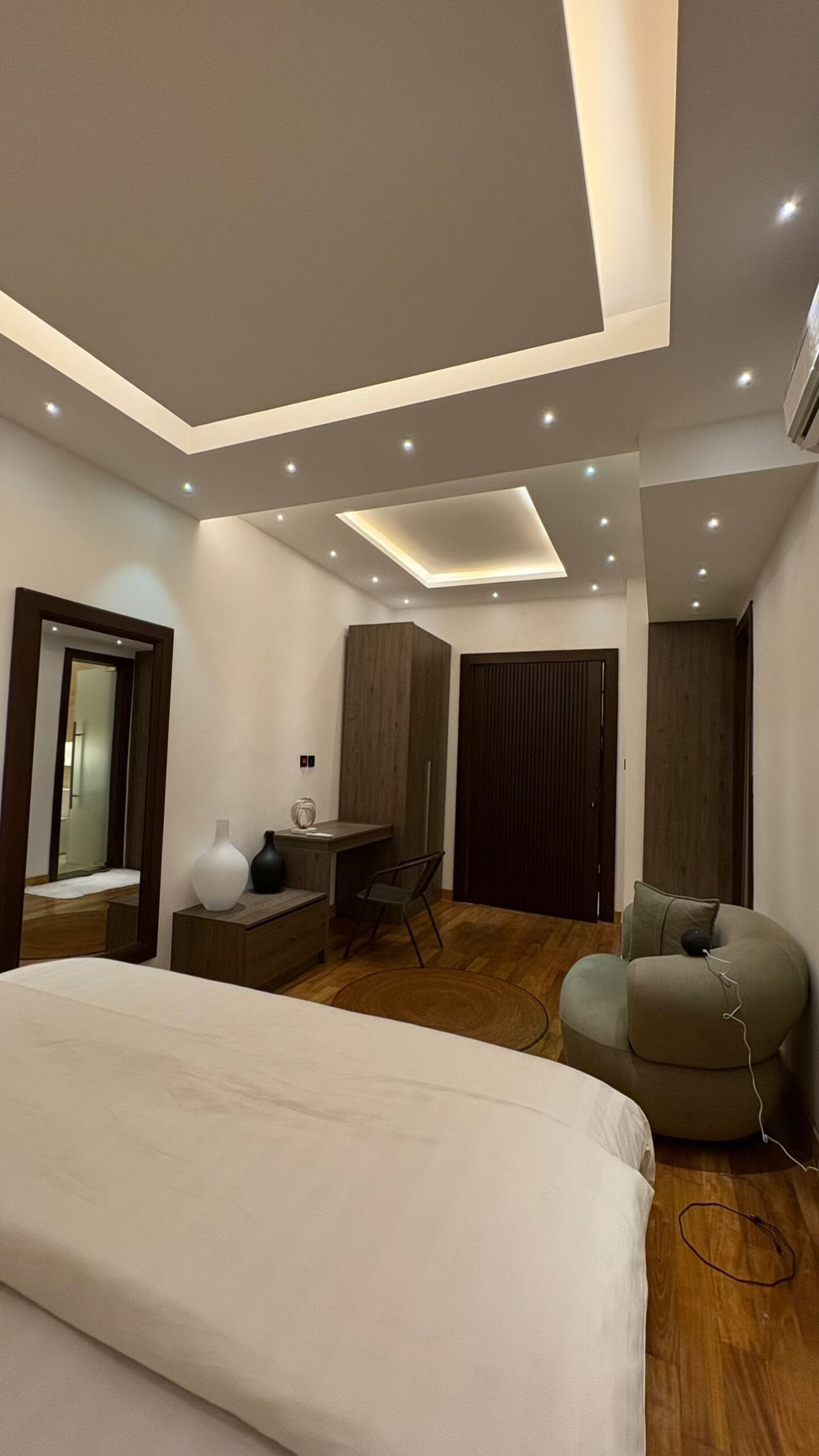 A modern bedroom with a bed, a desk, a chair, and a sofa.