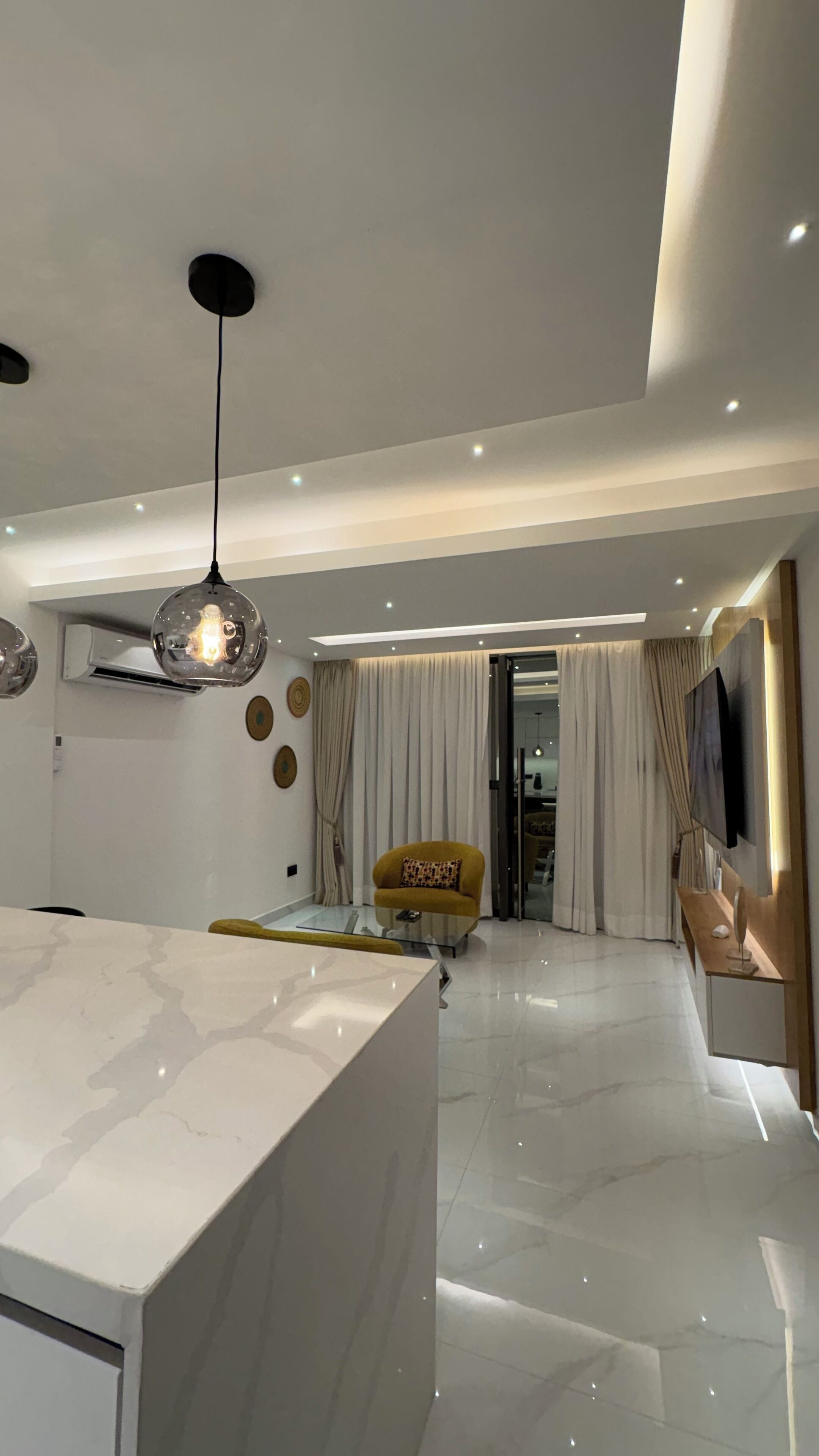 Una sala de estar moderna con una encimera de mármol, un sillón amarillo y una mesa de centro de vidrio.