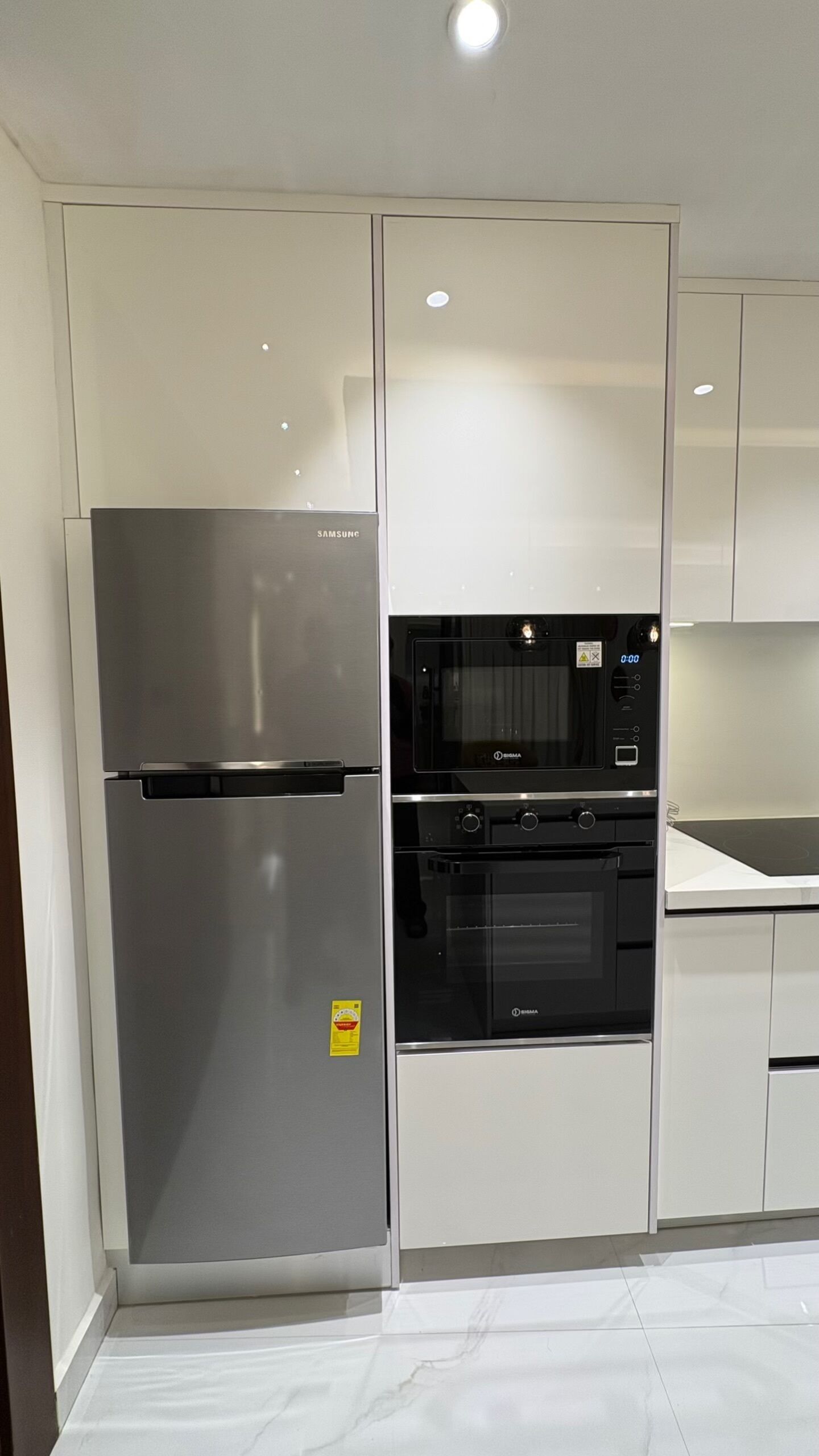 A modern kitchen with stainless steel appliances, including a refrigerator and oven, and white cabinetry.
