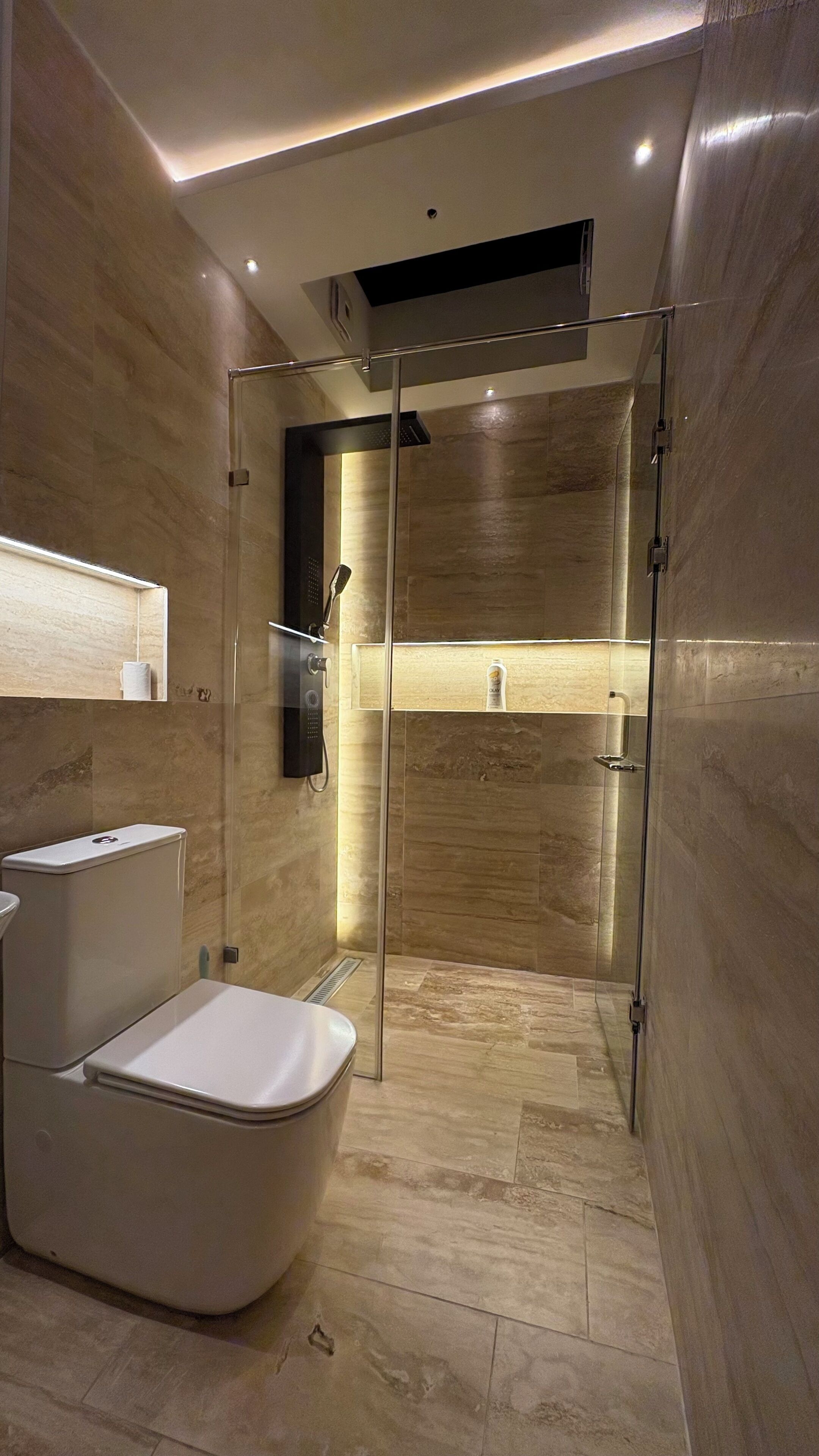 Une salle de bain moderne équipée de toilettes, d’une douche et d’un meuble-lavabo avec un miroir.