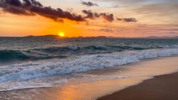 Une plage avec des vagues et un coucher de soleil.