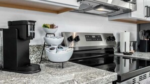Una cucina moderna con macchina da caffè espresso integrata, piano cottura in acciaio inossidabile e piani di lavoro in granito.