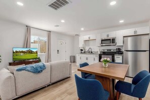 Ein modernes Wohnzimmer mit einer Couch, einem Holzesstisch und blauen Stühlen.