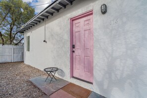 Ein Haus mit einer rosafarbenen Tür, einem kleinen runden Tisch und einer Fußmatte.