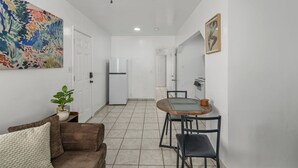 A compact kitchen with a refrigerator, a dining table with chairs, a ceiling fan, and a door leading to another room. - Casita Rosa - Cozy - Midtown Gem (Tucson)