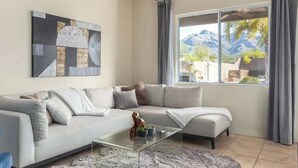 Una sala de estar moderna con un sofá modular, una mesa de centro de vidrio, una alfombra de piel y un ventanal con vistas a la montaña.