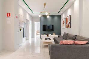 A modern living room with a grey sofa, a coffee table, and a TV mounted on the wall. - Warm modern apartment (Pireas)