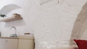 Una cocina compacta con un lavamanos empotrado, un estante de madera y un armario color beige.