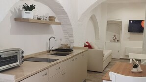 Una cocina moderna con una isla integrada, un lavaplatos y un tostador. Hay una mesa de comedor de madera con sillas y un televisor montado en la pared.