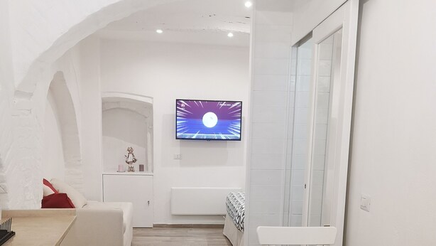 Una cocina moderna con armarios blancos, una mesa de comedor de madera y una pequeña planta en maceta.