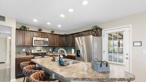 A modern kitchen with granite countertops, stainless steel appliances, and a central island with bar stools. - Private Pool Oasis. Perfect for Summer & Family Visits (Phoenix)