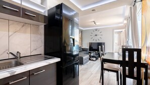 Een moderne keuken met een zwarte koelkast, een marmeren aanrechtblad en een eethoek met een tafel en stoelen.