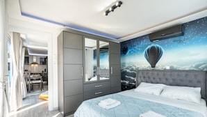 Een slaapkamer met een groot bed, een garderobe, een spiegel en een wanddecoratie van een luchtballon.