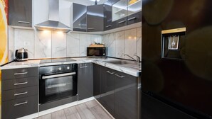 Een moderne keuken met donkere kastjes, een ingebouwde oven, een magnetron en een roestvrijstalen afzuigkap.