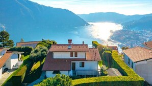 A coastal villa with a red-tiled roof, surrounded by lush greenery and overlooking a bay with mountains in the background. - Villa Citriodora  Cernobbio (Cernobbio)